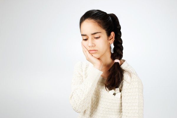 Young girl holding her cheek with TMJ pain