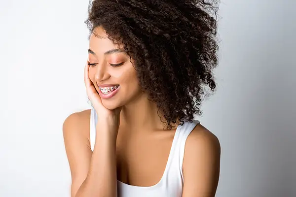 Young woman smiling confidently while wearing braces, showcasing the benefits of orthodontic treatment.