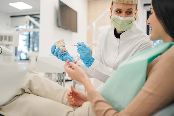 A happy patient listens while her orthodontist uses a dental model to educate her about the different orthodontic treatments available.